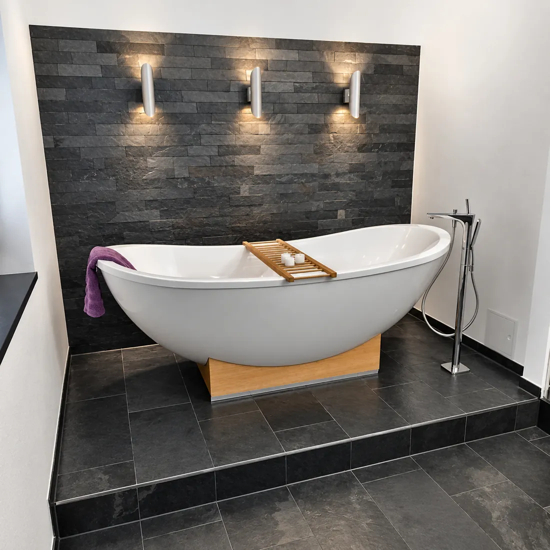 Referenzbad mit freistehender Badewanne und Schieferwand
